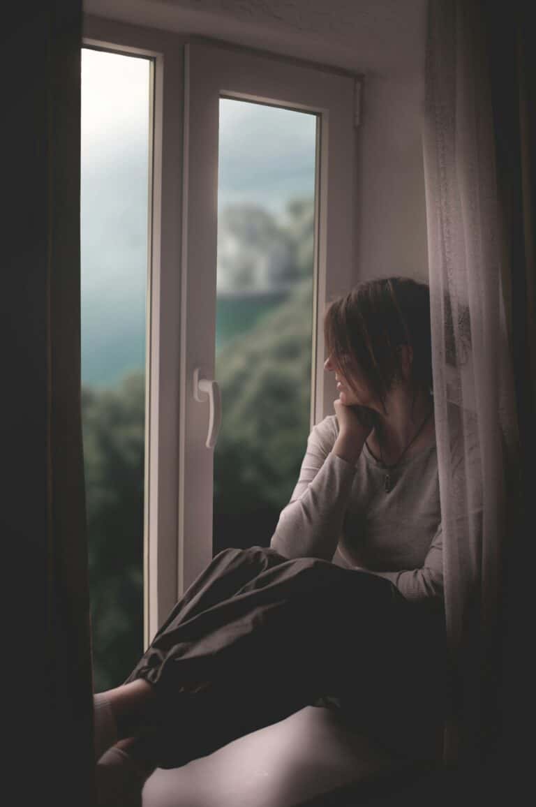 Woman in her fifties standing by an open window